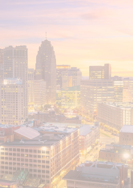 An aerial view of the Detroit cityscape with vibrant lights and a sunset in the sky behind it