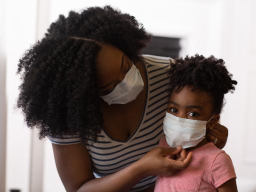 A woman and child wearing protective surgical masks. 