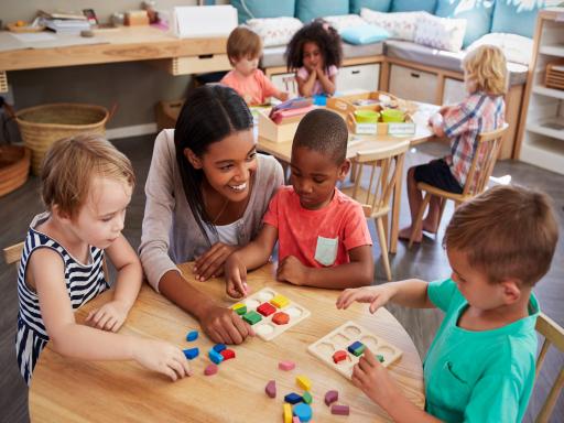 Teacher talking to children at a table and smiling