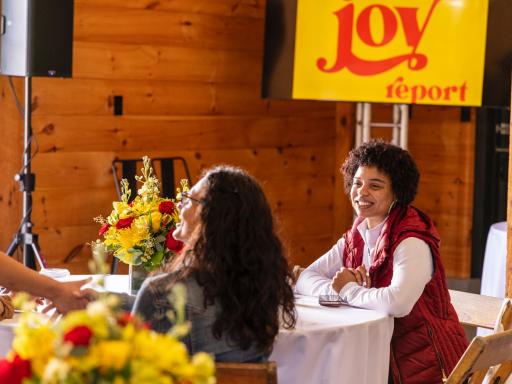 Three individuals smile and greet each other at the Song Foundation Joy Report event. Image Courtesy of the Song Foundation.
