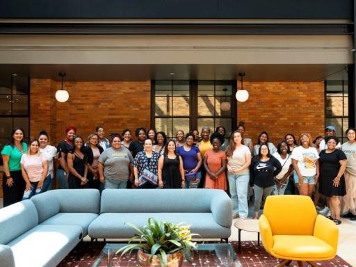A group of 30 women are gathered together and smiling for a posed photo.