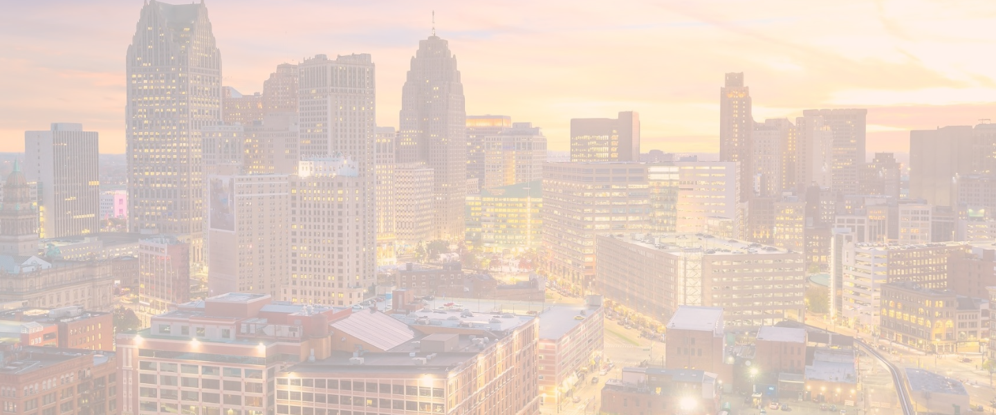 An aerial view of the Detroit cityscape with vibrant lights and a sunset in the sky behind it