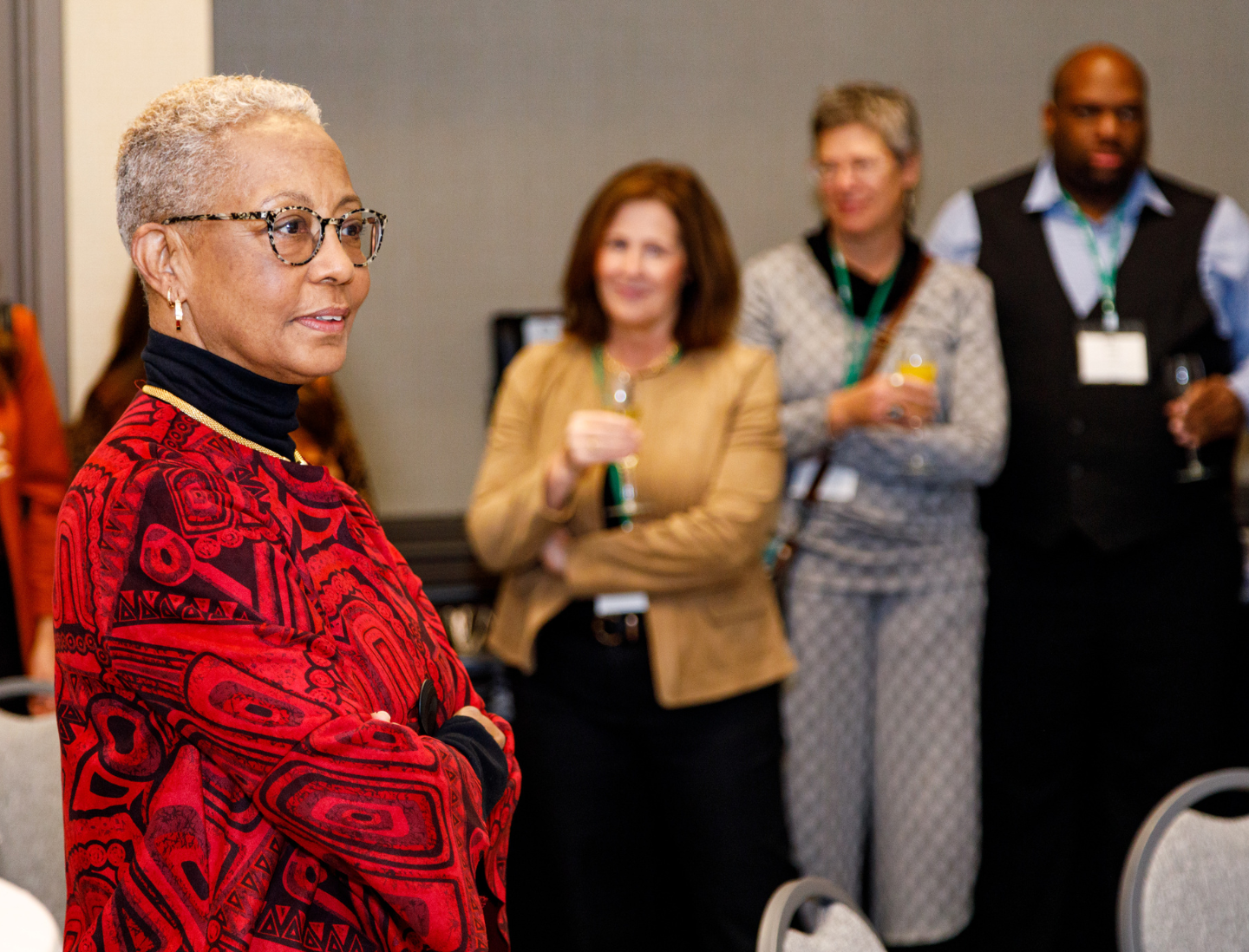 A photo of one of our awardees after her award presentation with colleagues getting ready in the back ground for a toast in her honor 