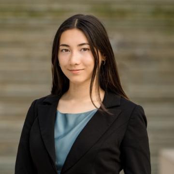 Headshot for Camille Gerville-Reache, wearing a black suit jacket and light blue blouse