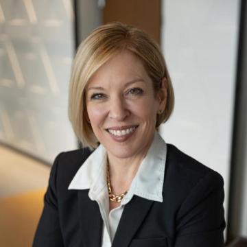 Headshot for Holli Seabury, who is wearing a suit jacket and collared shirt while smiling at the camera