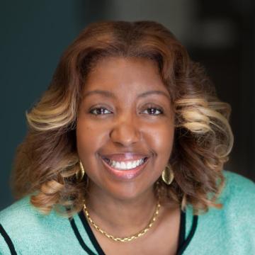 headshot for Shannon Polk, wearing a light teal sweater and smiling at the camera