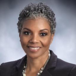 Headshot for Faye Alexander Nelson, wearing a black suit jacket and smiling at the camera