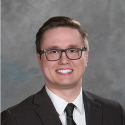 Headshot for Kayl Black, wearing a suit and smiling at the camera