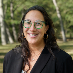 Headshot for Jennifer Heymoss, wearing a black suit jacket and smiling