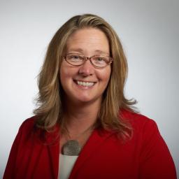 Headshot of Carrie Pickett-Erway wearing a red suit jacket, smiling 