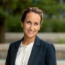 Headshot of Regina Cardenas in a blue suit jacket and white shirt, smiling and facing the camera