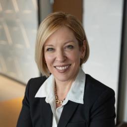 Headshot for Holli Seabury, who is wearing a suit jacket and collared shirt while smiling at the camera