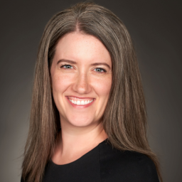 Headshot for Cara Binder-Kopchick who is looking at the camera and smiling, wearing a black long sleeve sweater