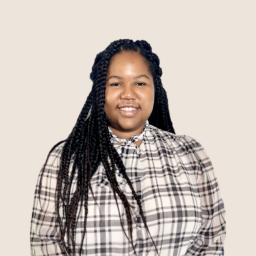 Headshot for Taylor Williams, wearing a plaid blouse and smiling at the camera